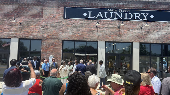 Neighbors and local officials gather for the ribbon-cutting grand opening of Main Street Laundry